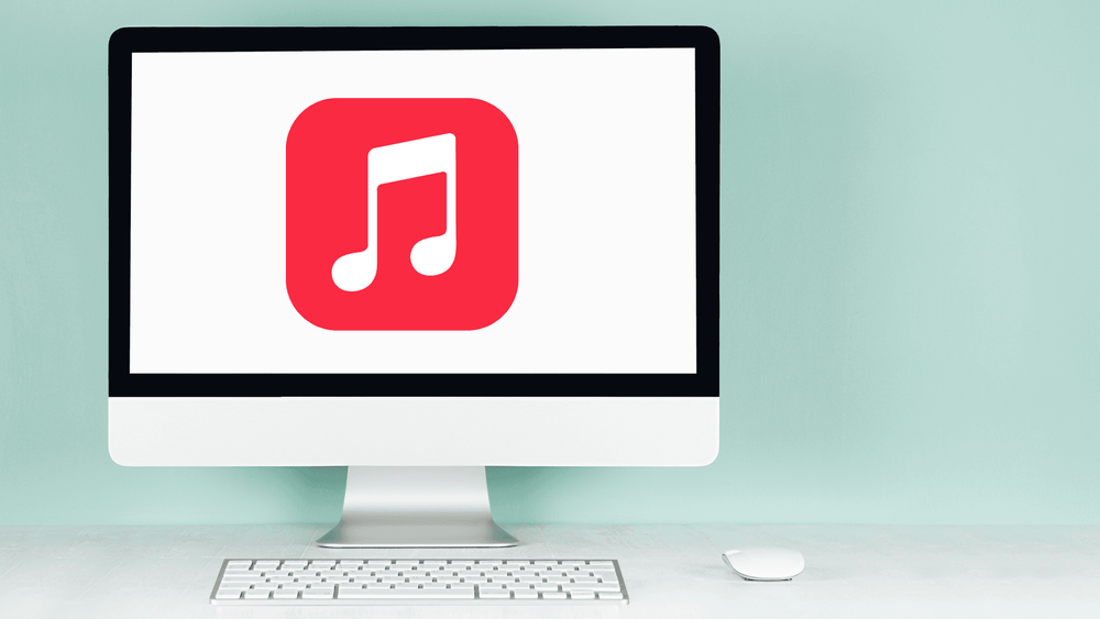 A desktop computer displaying Apple Music in browser, with a keyboard and mouse.
